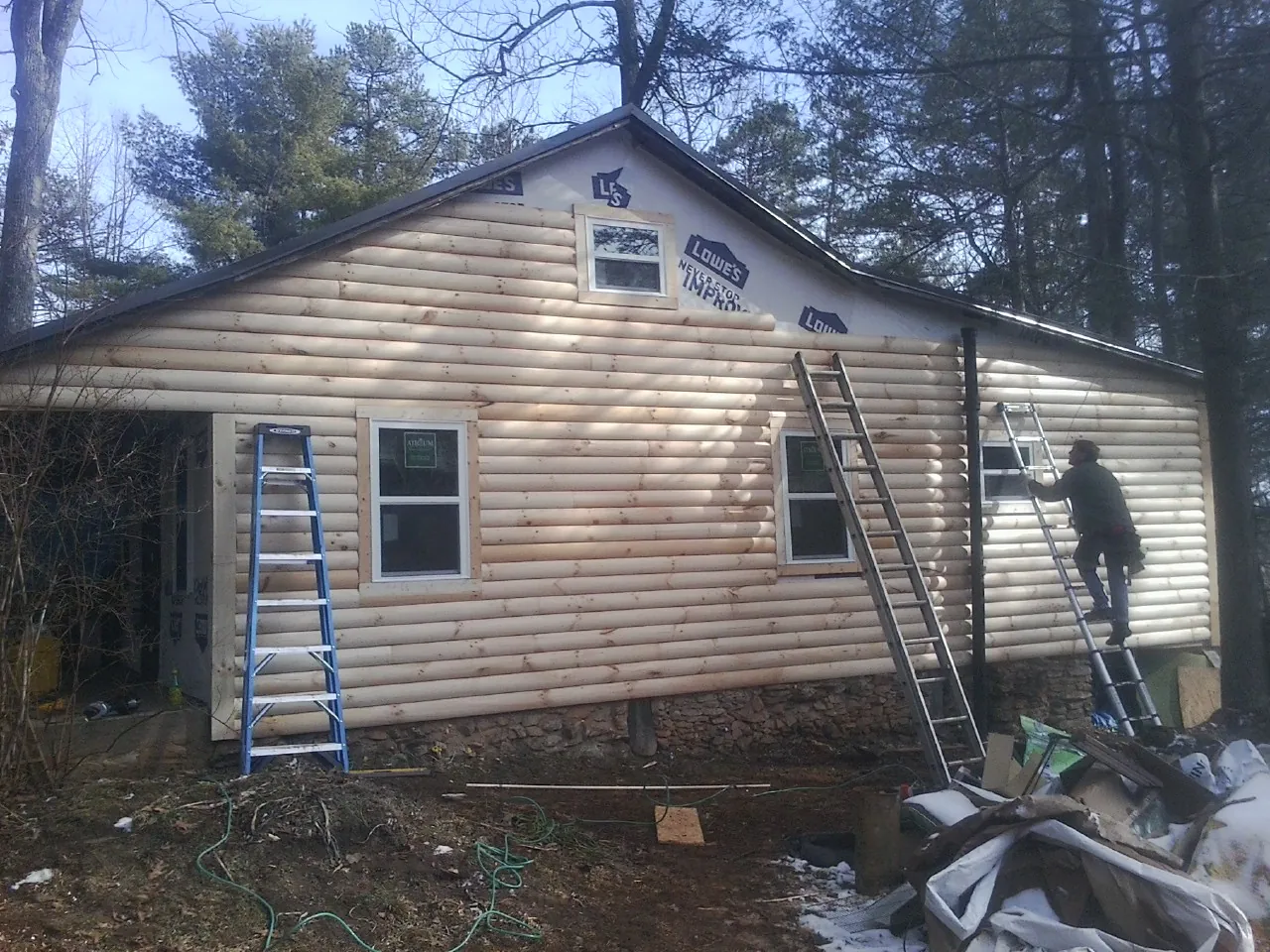 Ladders set against fresh log siding during an exterior remodel in Collins