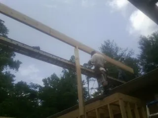 Carpenter setting a ridge beam over a new addition frame — Ice Dam Removal by Roofing Brothers in Collins