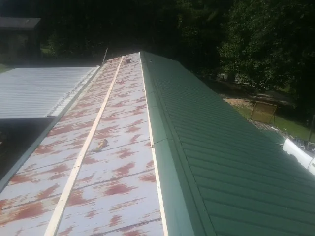 Old rusted panels beside newly installed green metal roofing — Wind Damage Roof Repair by Roofing Brothers in Collins