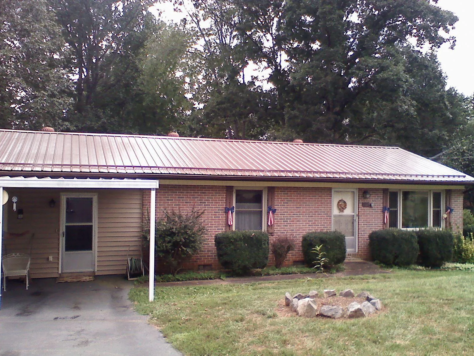 Bronze metal roof and carport on a brick ranch home — Roof Repair work by our crew in Collins
