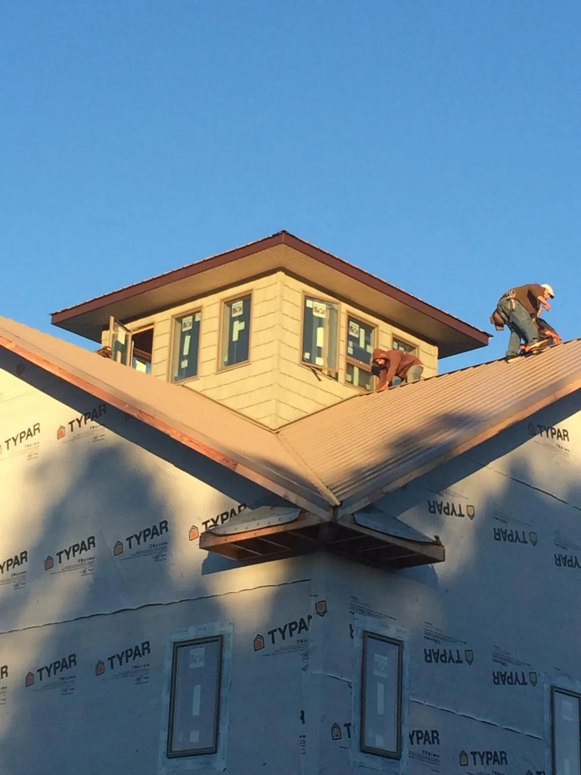 Roofers working around a rooftop cupola on a new metal roof at sunset — Roof Waterproofing in Collins by Roofing Brothers